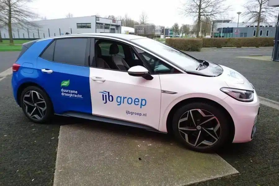 Elektrische personenauto met autoreclame van IJB Groep uit Lemmer in herkenbare huisstijl, verzorgd door Dox.