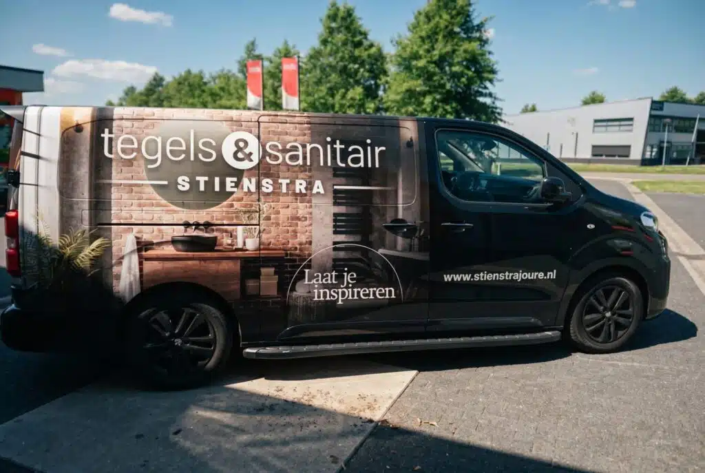 Zwarte bedrijfswagen met voertuigreclame van Tegels & Sanitair Stienstra uit Joure, bestickerd door Dox.